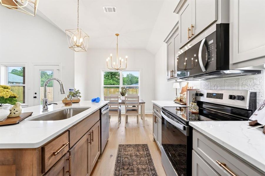 Modern kitchen featuring a large island with an undermount sink, quartz countertops, stainless steel appliances, and a tiled backsplash