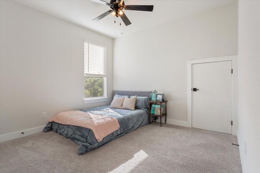 Bedroom with light colored carpet and a ceiling fan