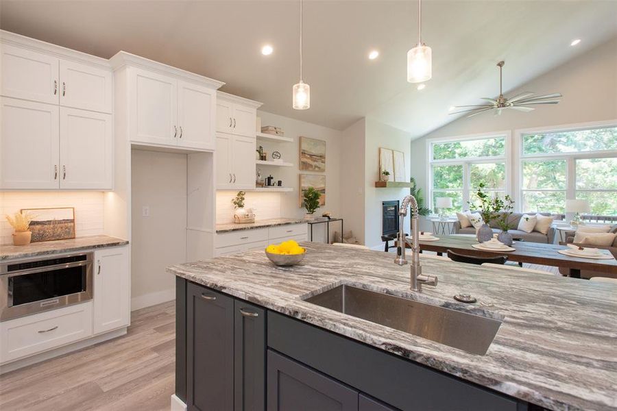 Kitchen featuring pendant lighting, sink, custom cabinets, lofted ceiling, and ceiling fan