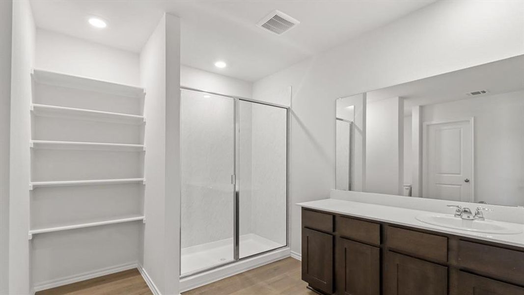 Bathroom with a shower stall, light wood-style floors, and vanity