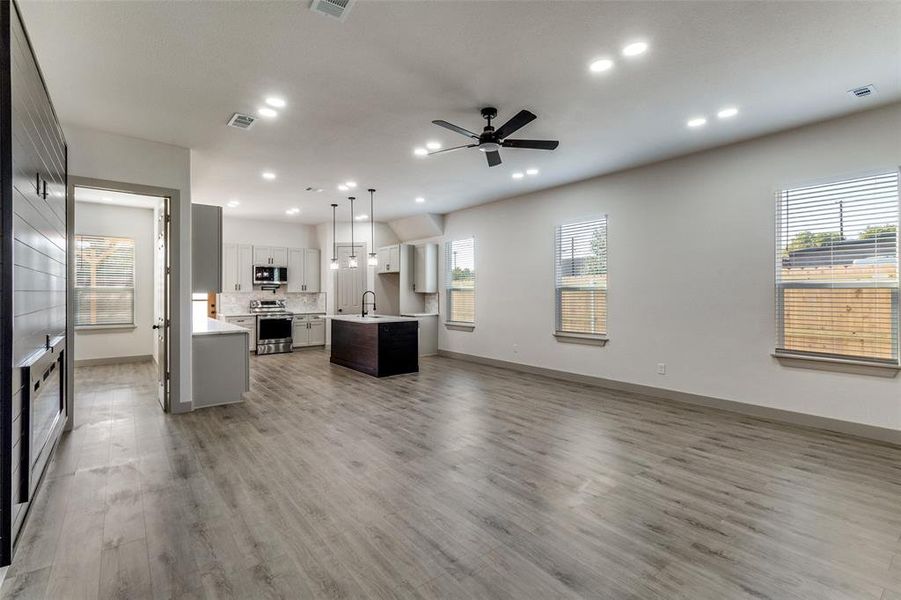 Unfurnished living room featuring plenty of natural light, light wood finished floors, ceiling fan, and recessed lighting Unfurnished living room featuring plenty of natural light, light wood finished floors, ceiling fan, and recessed lighting