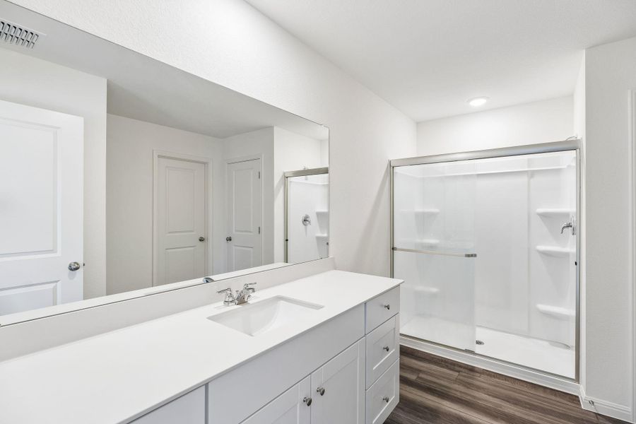Bathroom with a stall shower, dark wood-style floors, and vanity