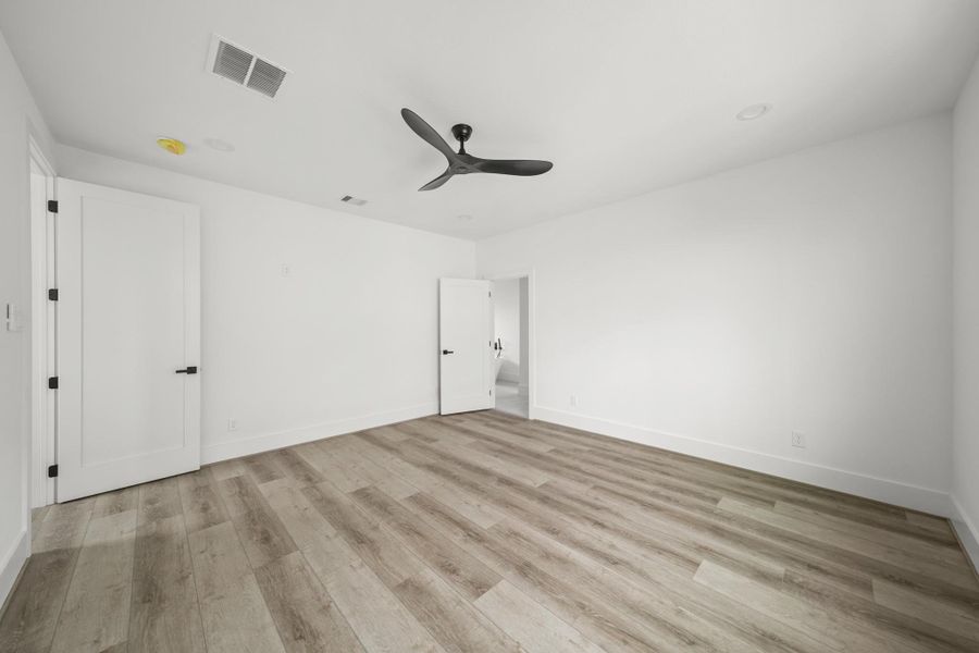 Corner view of the primary bedroom featuring the entrance to the primary bath on the left. Corner view of the primary bedroom featuring the entrance to the primary bath on the left.