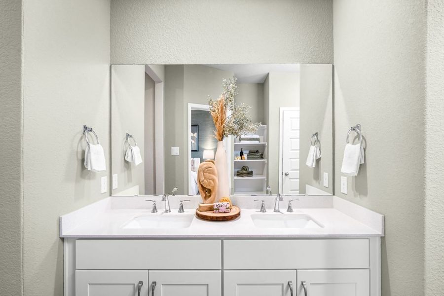 Image of the primary bathroom with light green walls, white vanity with white countertops.