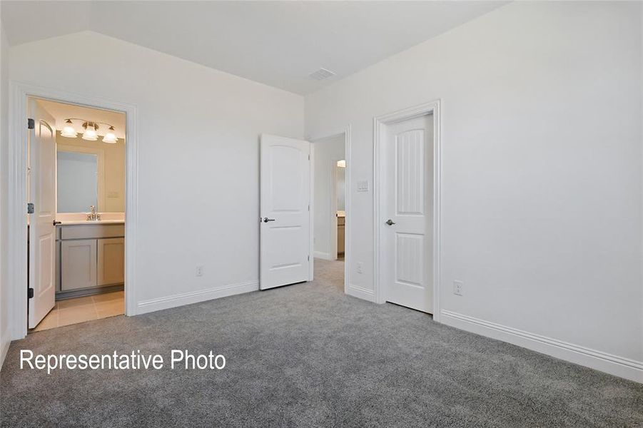 Unfurnished bedroom with lofted ceiling, sink, light carpet, and connected bathroom