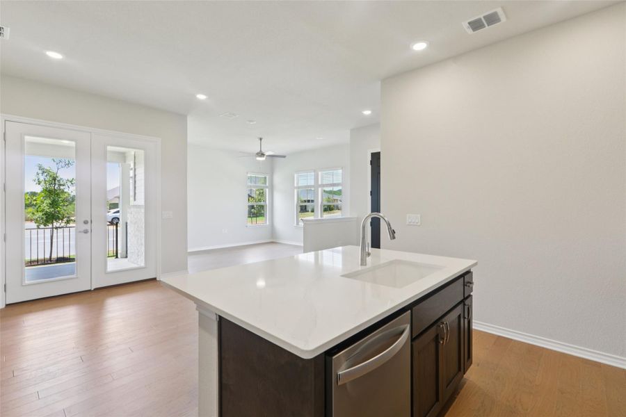 Kitchen featuring dark brown cabinetry, light wood finished floors, recessed lighting, a kitchen island with sink, and open floor plan Kitchen featuring dark brown cabinetry, light wood finished floors, recessed lighting, a kitchen island with sink, and open floor plan