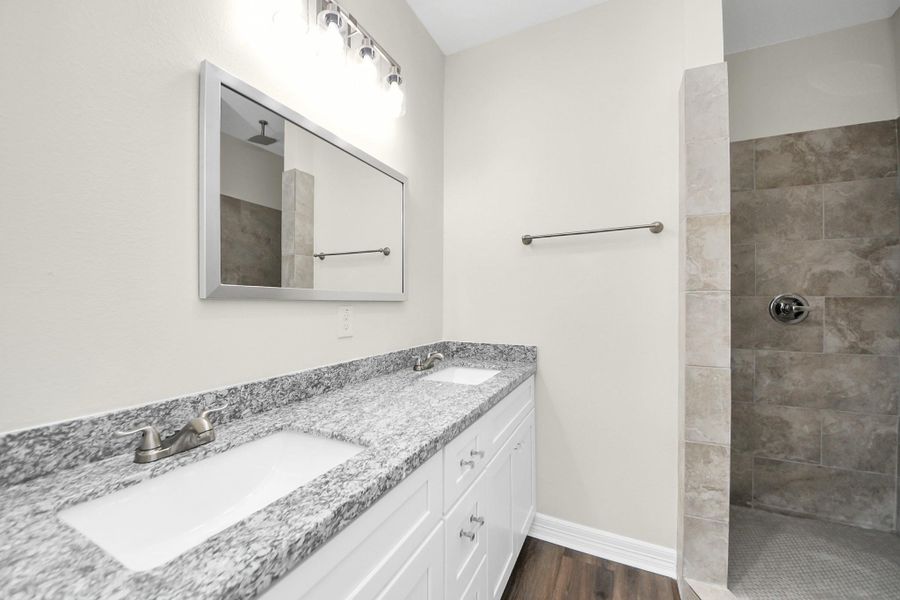 The primary bathroom combines elegance and practicality, showcasing a stunning mud-set shower with a rainfall showerhead, a spacious granite vanity with dual sinks, and plenty of cabinet space to keep everything organized and within reach - (representation photo).