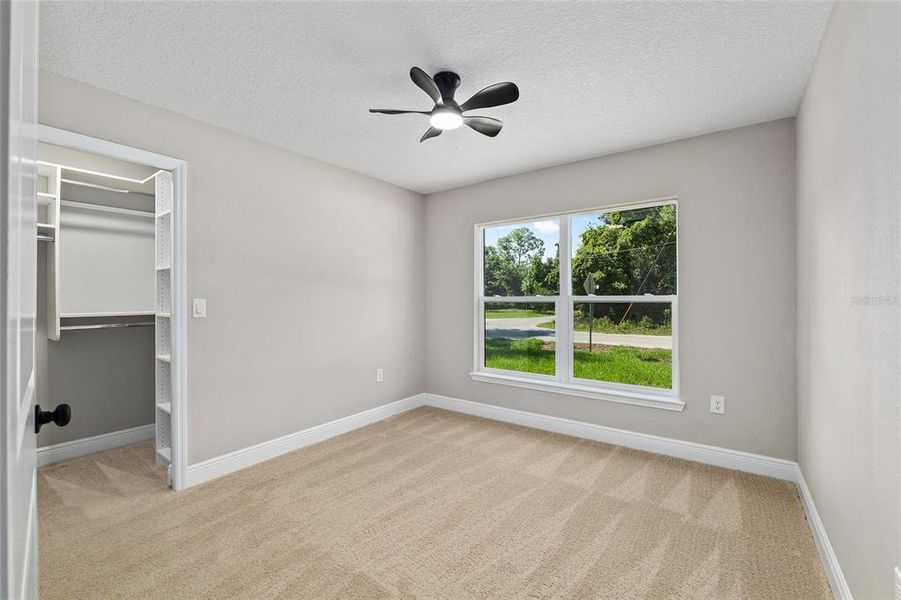 Bedroom 3 with ceiling fan and custom closet