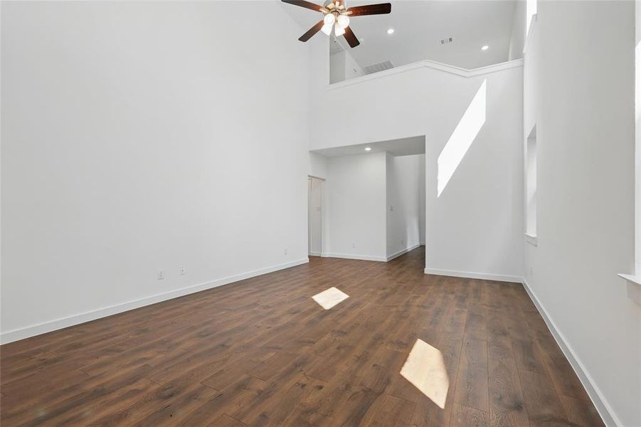 Unfurnished living room with dark wood finished floors, a high ceiling, a ceiling fan, and recessed lighting