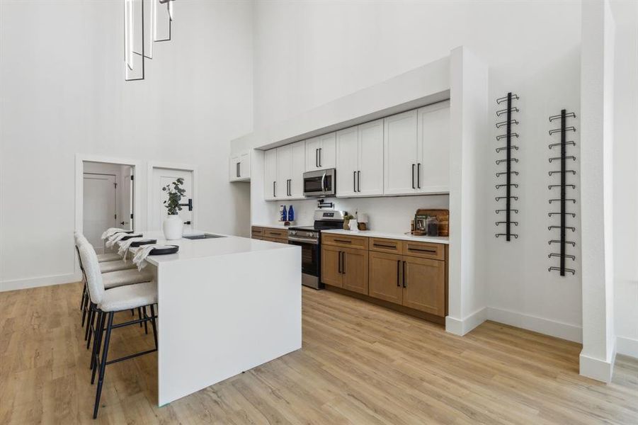 Kitchen featuring white cabinetry, a kitchen breakfast bar, a kitchen island, a high ceiling, and stainless steel appliances