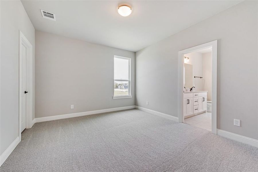 Unfurnished bedroom with connected bathroom, sink, and light colored carpet