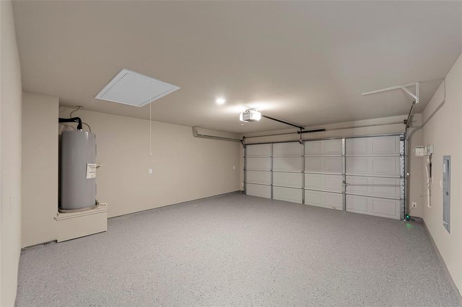 Garage featuring electric water heater, electric panel, and a garage door opener