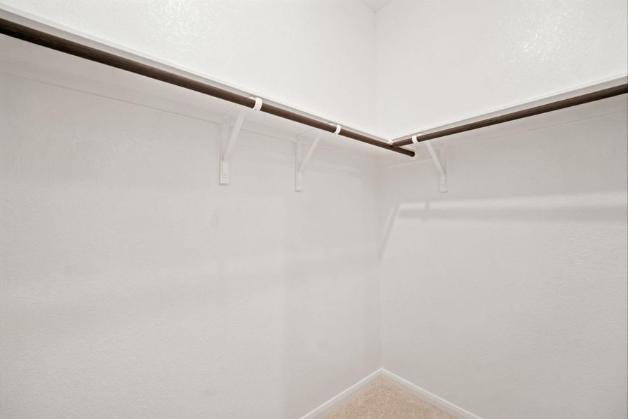 Ample hanging rods and shelving wrap around this neutral walk-in storage space.