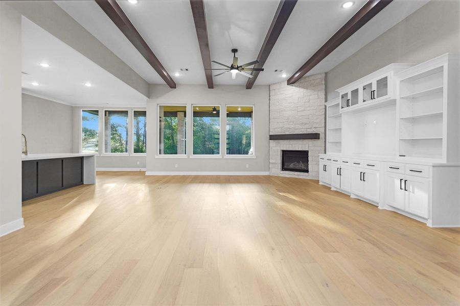 Open-concept living room with wood flooring, recessed lighting, and large windows overlooking the backyard. Open-concept living room with wood flooring, recessed lighting, and large windows overlooking the backyard.