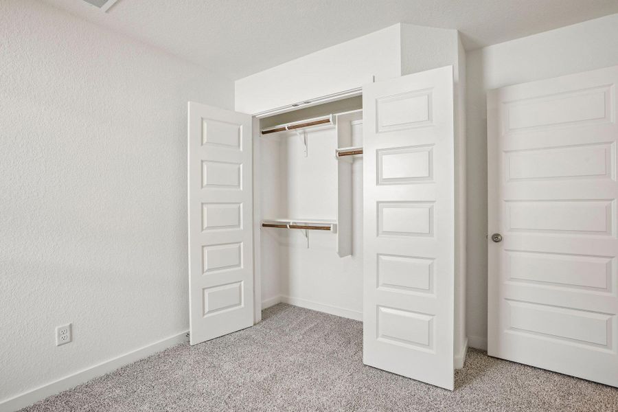 Plush carpeting and paneled closet doors define this functional bedroom space.