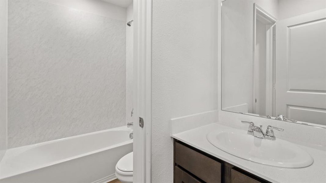 Bathroom featuring a dark wood-finish vanity with an undermount sink, a chrome faucet, and a large mirror