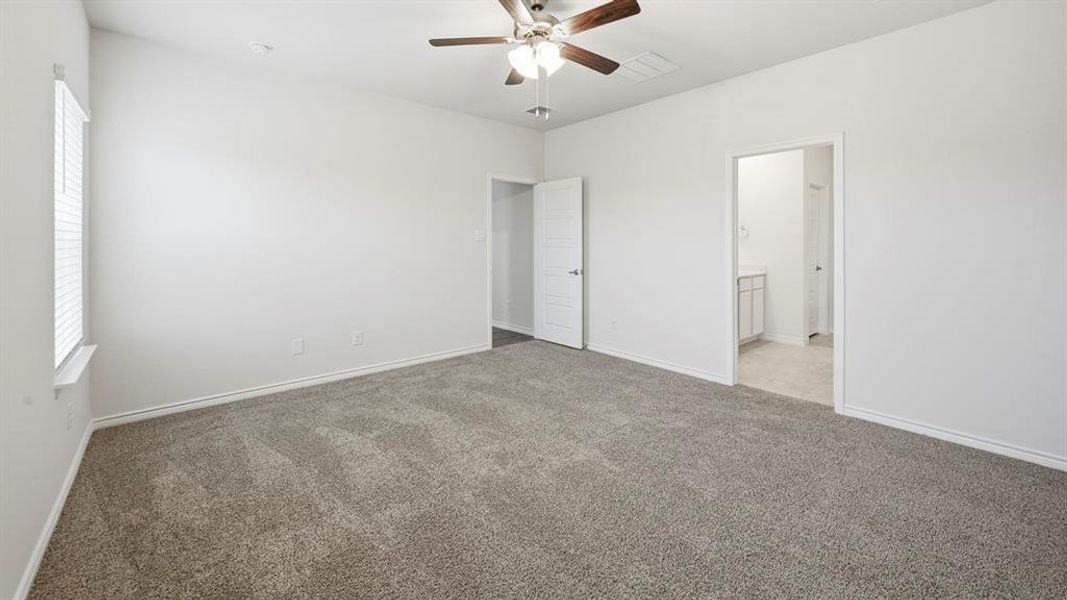 Spacious carpeted room featuring a ceiling fan, window with blinds, and white panel doors