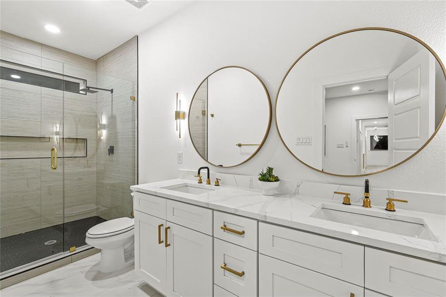 Bathroom featuring double vanity, recessed lighting, a shower stall, and light marble finish flooring