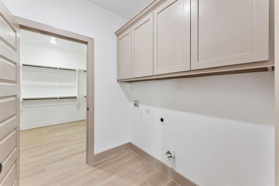 Laundry room featuring gas dryer hookup, light wood-style flooring, hookup for a washing machine, cabinet space, and hookup for an electric dryer Laundry room featuring gas dryer hookup, light wood-style flooring, hookup for a washing machine, cabinet space, and hookup for an electric dryer