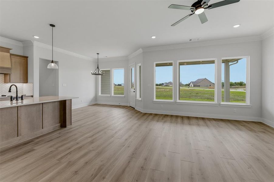 Spacious room featuring wood-finish flooring, a contemporary ceiling fan, and multiple large windows