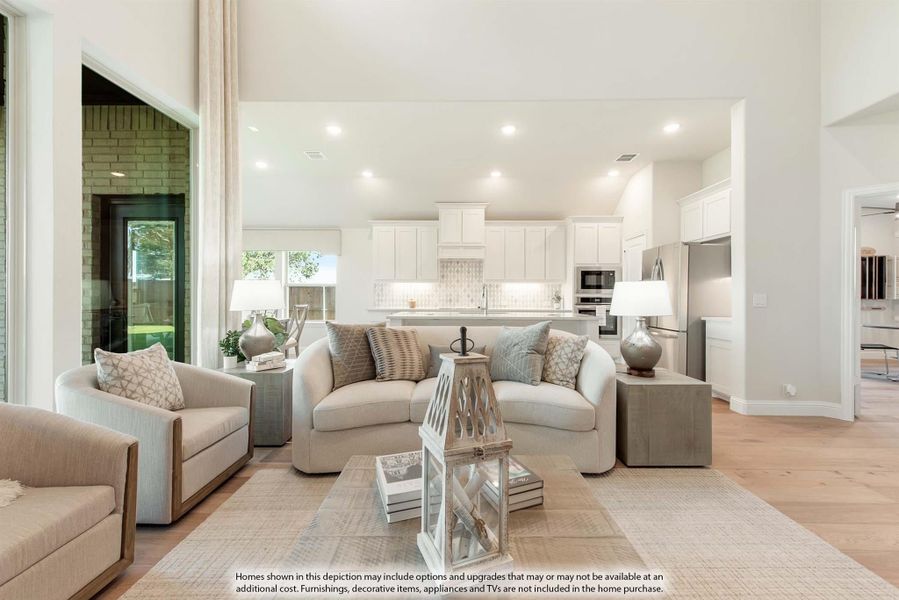 Open-concept living room with high ceilings, neutral furniture, and white kitchen visible in background