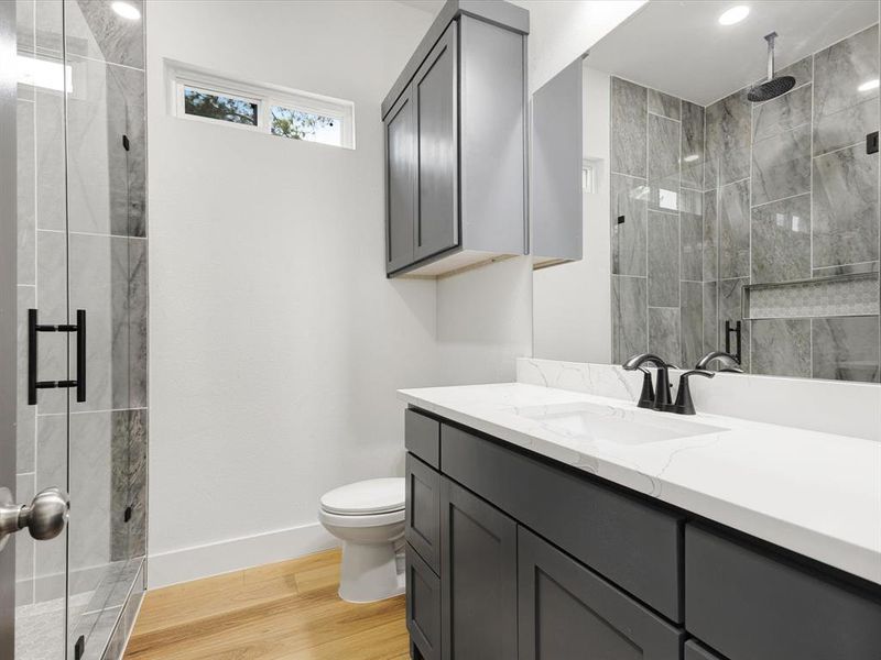 Full bathroom featuring a marble finish shower, vanity, and light wood-type flooring Full bathroom featuring a marble finish shower, vanity, and light wood-type flooring