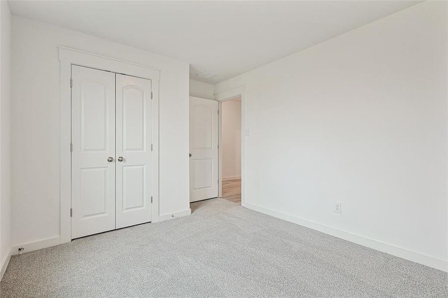 Unfurnished bedroom with light colored carpet and a closet