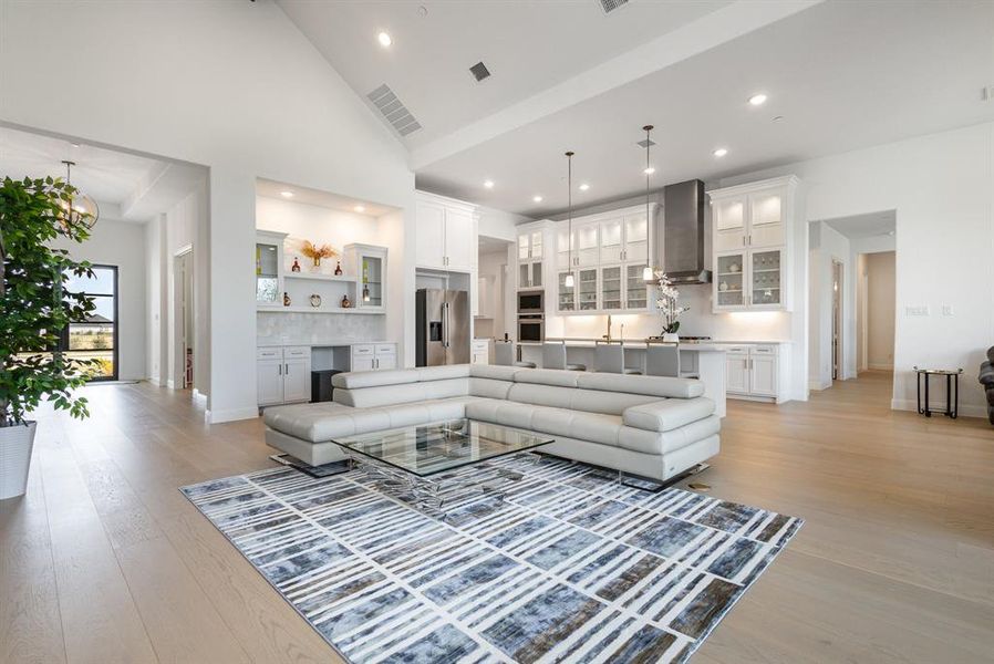 Living room featuring high vaulted ceiling, light wood-style floors, and recessed lighting