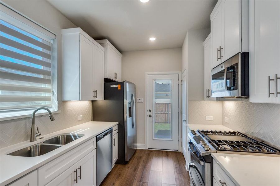 Kitchen featuring backsplash, white cabinets, appliances with stainless steel finishes, and recessed lighting Kitchen featuring backsplash, white cabinets, appliances with stainless steel finishes, and recessed lighting