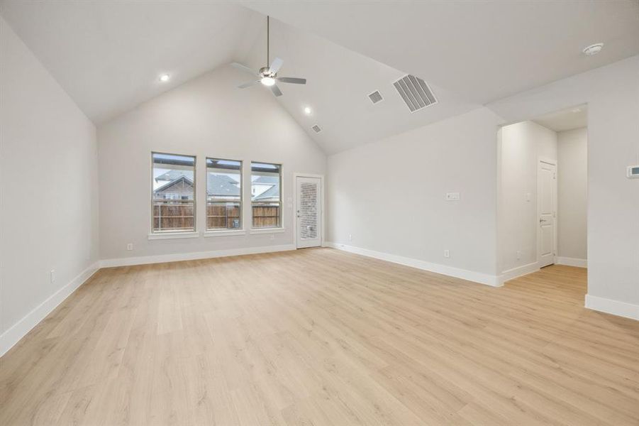 Unfurnished living room featuring ceiling fan, high vaulted ceiling, and light wood-type flooring