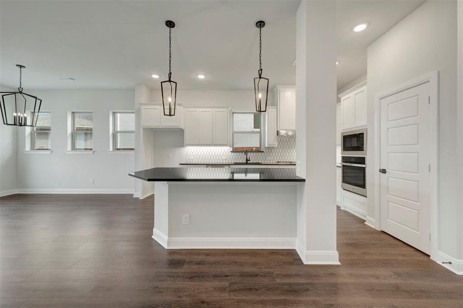 Kitchen featuring dark countertops, backsplash, dark wood-style flooring, and white cabinets