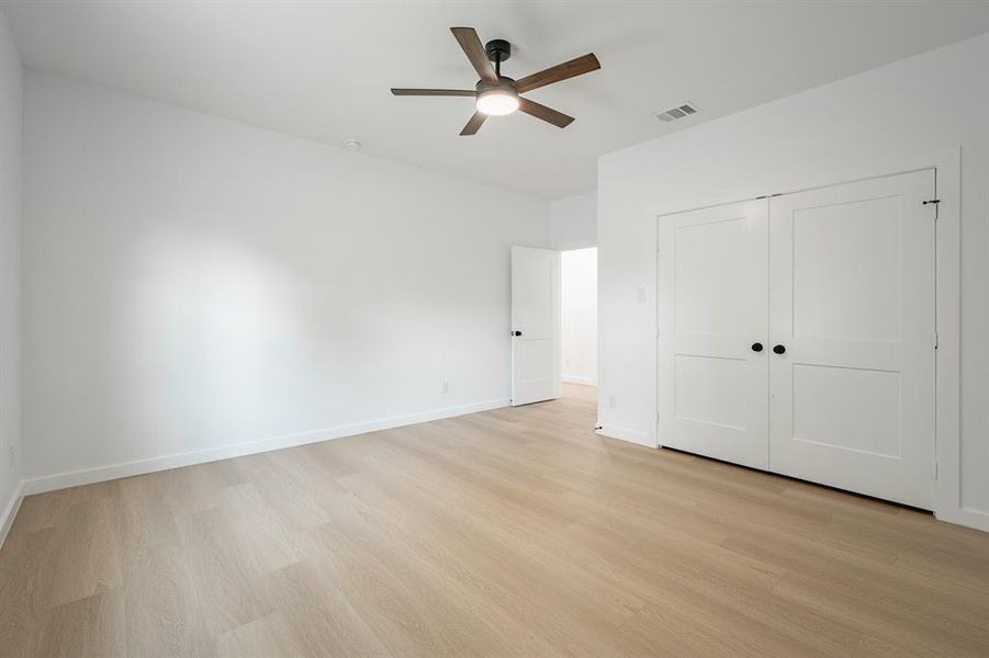 Unfurnished bedroom with light wood finished floors, a closet, and a ceiling fan Unfurnished bedroom with light wood finished floors, a closet, and a ceiling fan