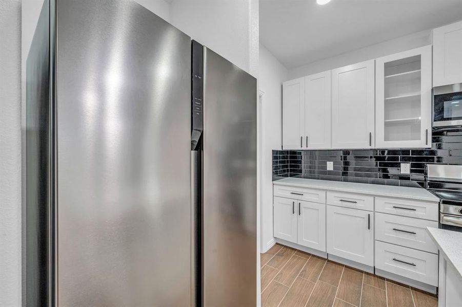 Kitchen with stainless steel appliances, white cabinetry, and tasteful backsplash