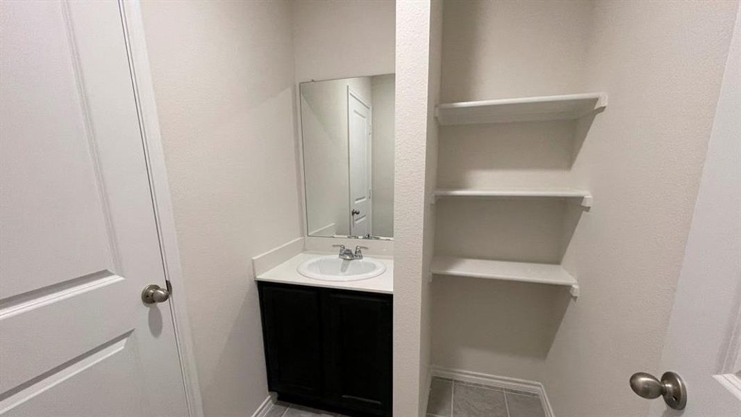 Vanity with dark wood cabinetry, white countertop, integrated sink, and wall-mounted mirror Vanity with dark wood cabinetry, white countertop, integrated sink, and wall-mounted mirror