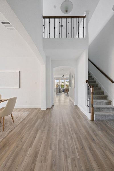 Unfurnished living room featuring light wood-style flooring, a high ceiling, and arched walkways Unfurnished living room featuring light wood-style flooring, a high ceiling, and arched walkways