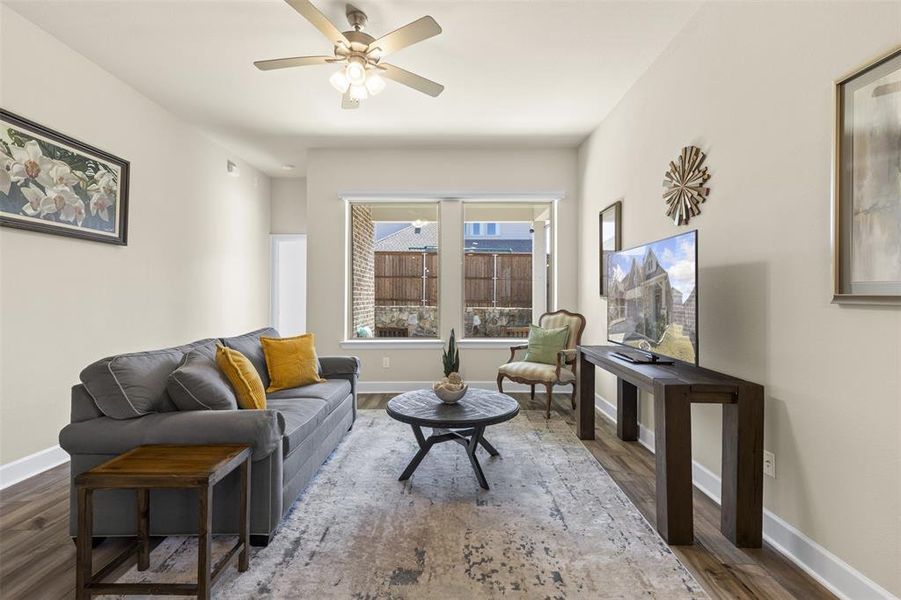 Living area with wood finished floors, a ceiling fan, and baseboards