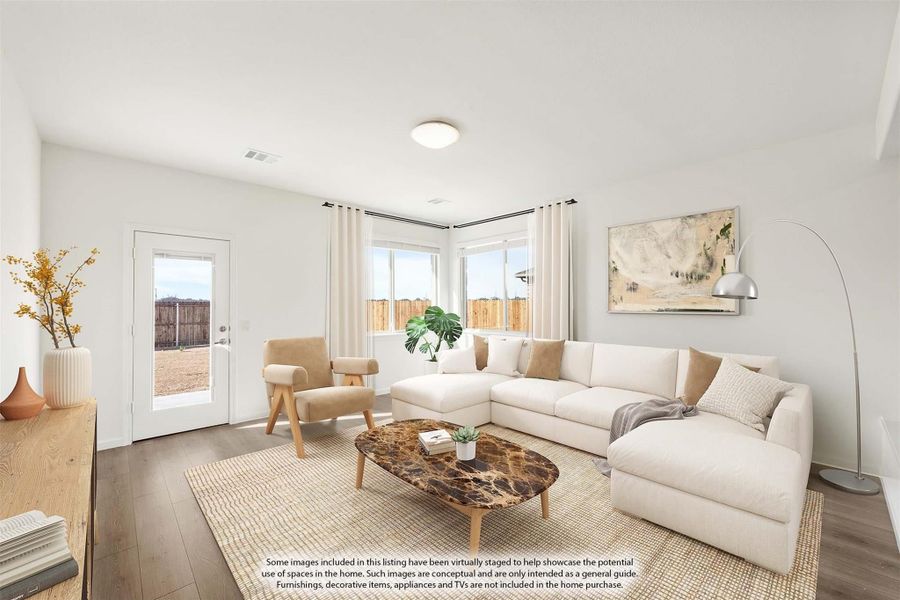Living room with white sectional sofa, hardwood floors, and large windows with backyard door access
