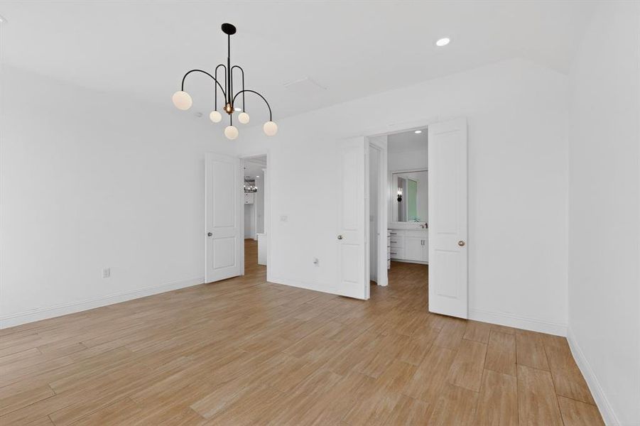 Spacious interior room featuring light wood-finish flooring, crisp white walls, and a contemporary black chandelier with spherical light fixtures Spacious interior room featuring light wood-finish flooring, crisp white walls, and a contemporary black chandelier with spherical light fixtures