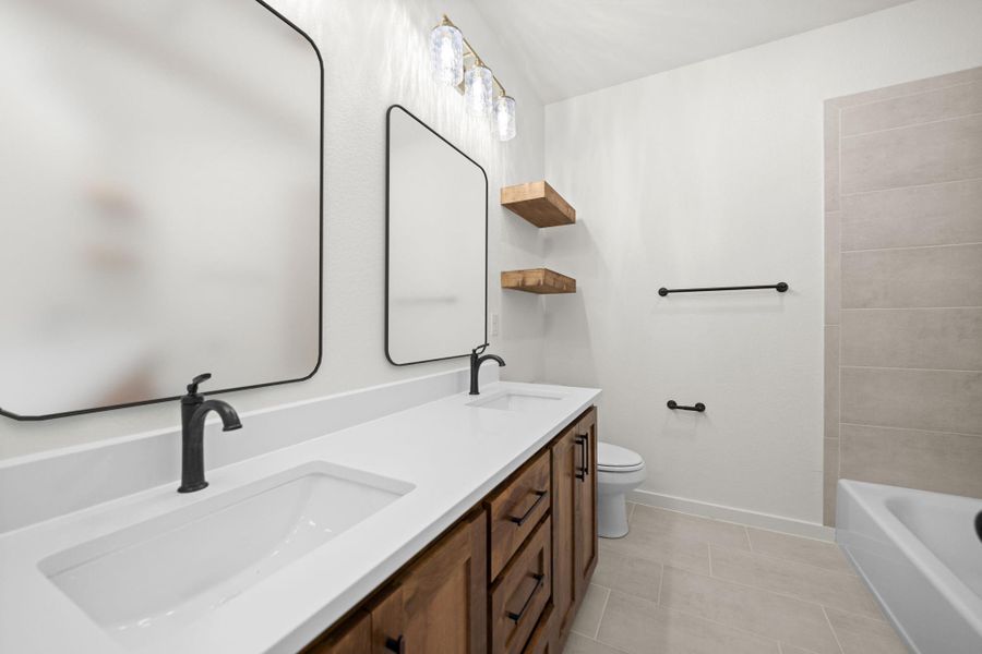 Dual vanity with sleek fixtures offers ample space and modern elegance in this primary bathroom. Dual vanity with sleek fixtures offers ample space and modern elegance in this primary bathroom.