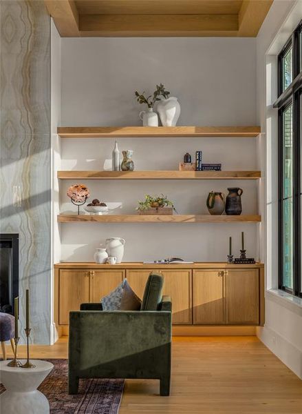 Built-in shelving and cabinetry with warm wood finishes, a large black-framed window, and wood-finish flooring