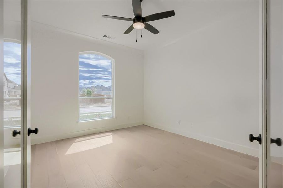 Light wood-finish flooring with a contemporary black ceiling fan and light fixture Light wood-finish flooring with a contemporary black ceiling fan and light fixture