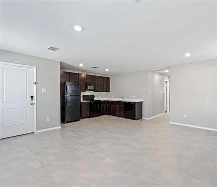 Kitchen featuring light countertops, dark brown cabinetry, open floor plan, black appliances, and recessed lighting