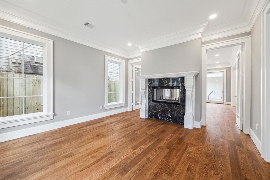 This light filled formal living room/study/music room features hardwood floors, high ceiling, beautiful crown molding and a stylish double-sided fireplace with a marble finish and flanked by doors that open to the den and can be closed for more privacy.