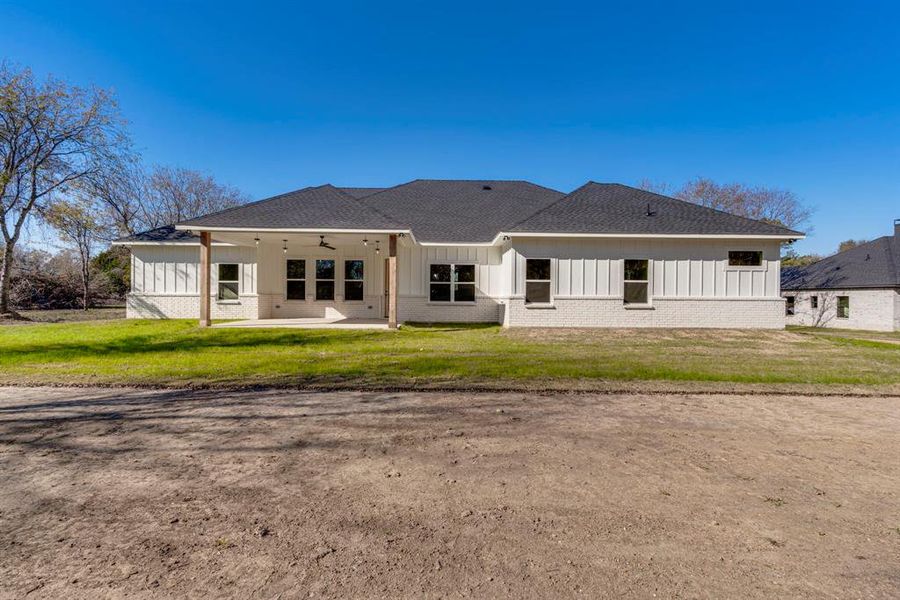 Back of house featuring ceiling fan, a patio area, and a yard