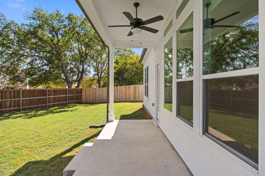Fenced backyard with ceiling fan and a patio area