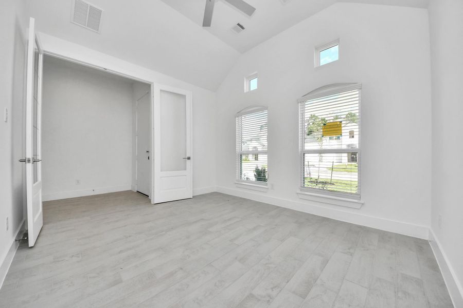 Experience the perfect blend of sophistication and warmth in this home office, boasting elegant wood-look tile flooring and flooded with natural light from expansive windows and French doors.
