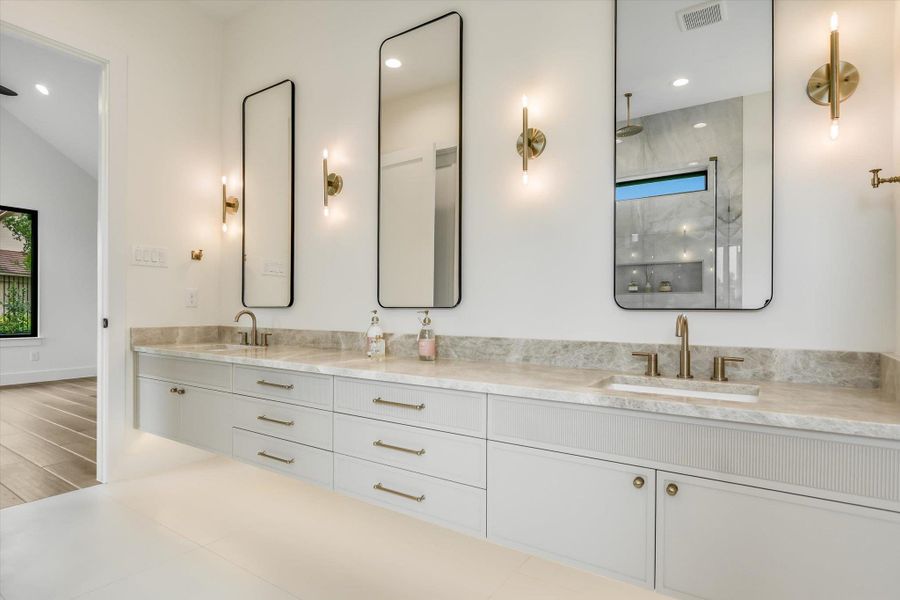Floating dual vanity with integrated sinks, stone countertop, and contemporary brass fixtures