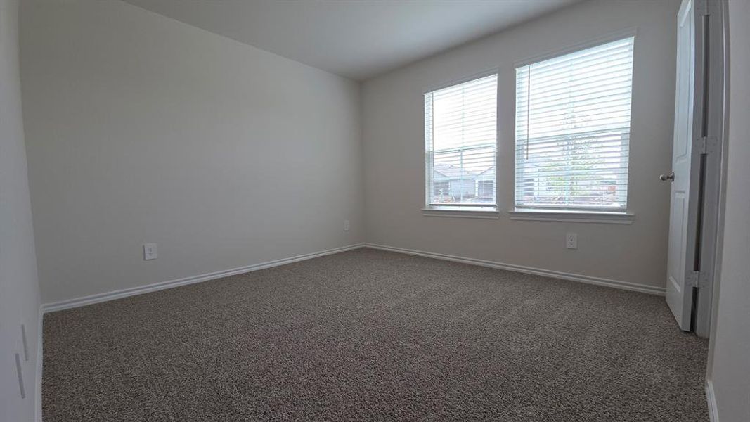 Carpeted interior room featuring two windows with horizontal blinds, neutral wall tones, and white trim