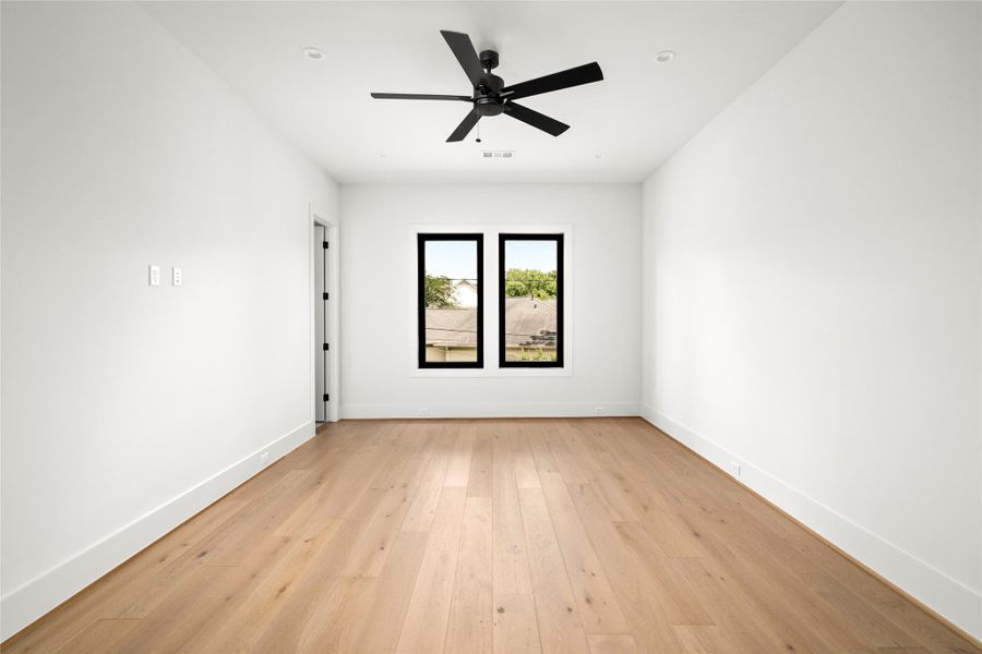 Secondary bedroom with high ceilings, wood floors, and abundant natrual light.