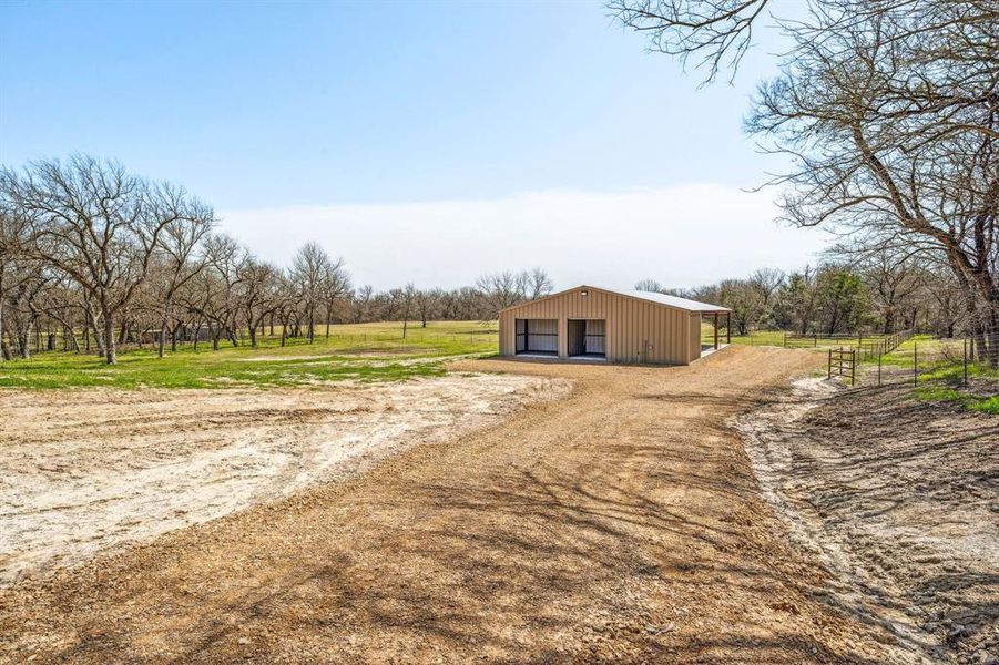View of yard featuring fence, an outbuilding, dirt driveway, and a detached garage